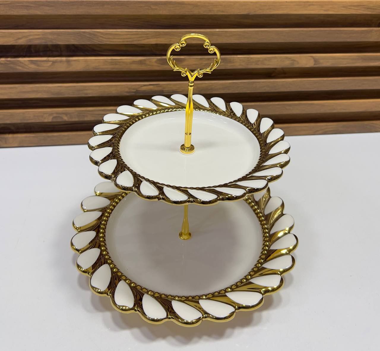 طبق تقديم مزدوج بطبقتين مع حامل ذهبي، تصميم أنيق ولمسة فخامة باللون الأبيض والذهبي.